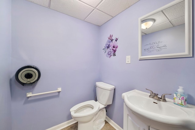 bathroom with tile flooring, sink, a paneled ceiling, and toilet