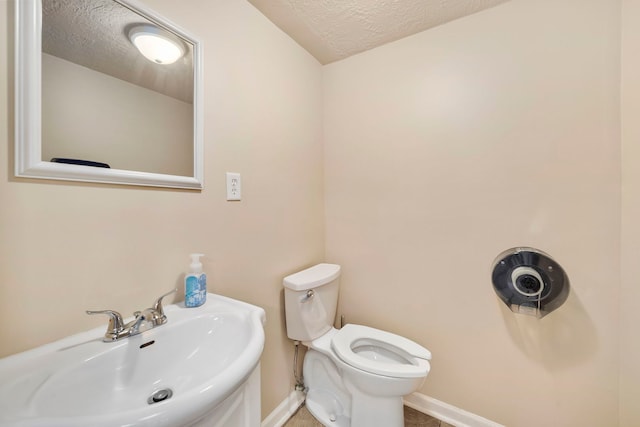 bathroom featuring a textured ceiling, sink, and toilet