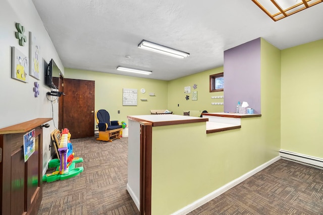 kitchen with dark colored carpet, a textured ceiling, kitchen peninsula, and a baseboard radiator