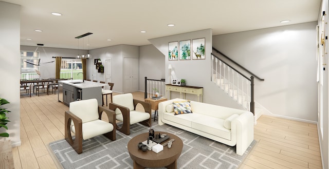 living room with an inviting chandelier, sink, and light hardwood / wood-style flooring