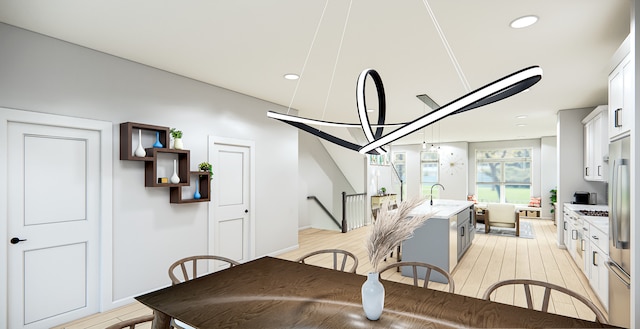 dining room with sink, an inviting chandelier, and light wood-type flooring