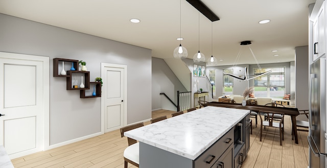 kitchen with stainless steel fridge, light hardwood / wood-style flooring, a kitchen island, and pendant lighting