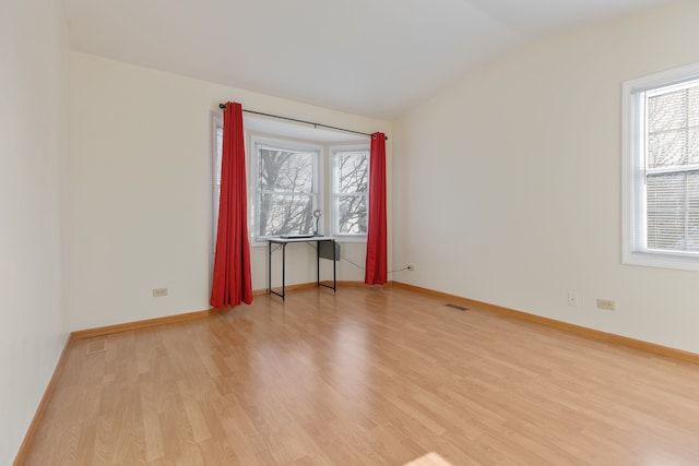 empty room featuring vaulted ceiling and light hardwood / wood-style flooring