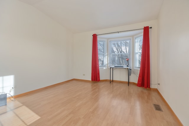 unfurnished room with hardwood / wood-style flooring and lofted ceiling