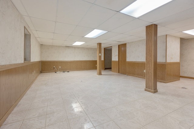 basement with a paneled ceiling and light tile patterned flooring