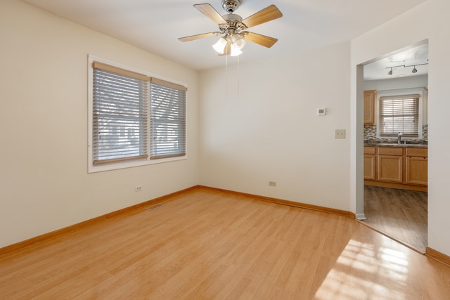 spare room featuring light wood-type flooring, sink, and ceiling fan