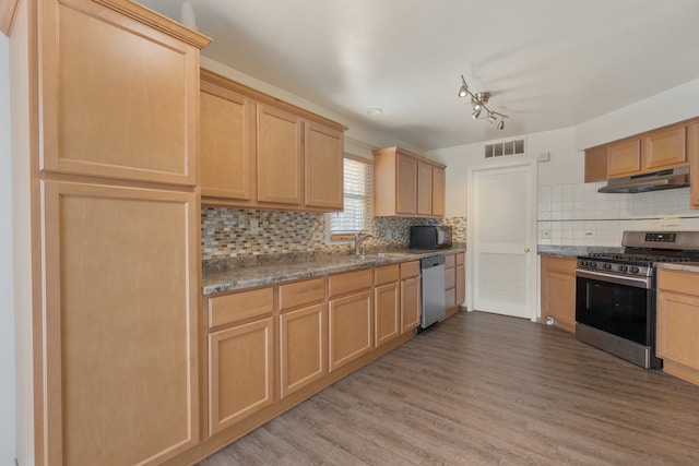 kitchen featuring appliances with stainless steel finishes, light hardwood / wood-style flooring, track lighting, and backsplash