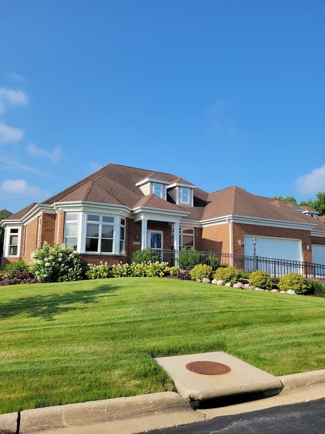 view of front of house with a garage, brick siding, and a front lawn