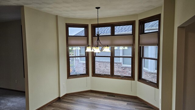 unfurnished dining area featuring hardwood / wood-style floors and a notable chandelier