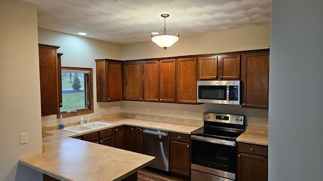 kitchen featuring sink, hanging light fixtures, dark hardwood / wood-style floors, kitchen peninsula, and stainless steel appliances