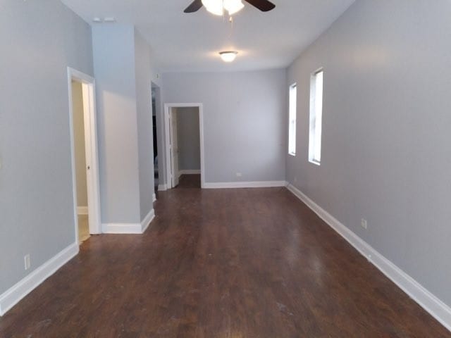 empty room with ceiling fan and dark hardwood / wood-style flooring