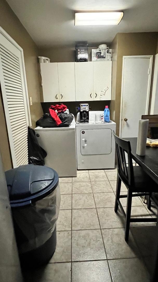 clothes washing area featuring cabinets, washer and dryer, and light tile patterned floors