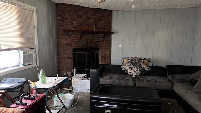 living room featuring wood walls, a textured ceiling, cooling unit, and a brick fireplace