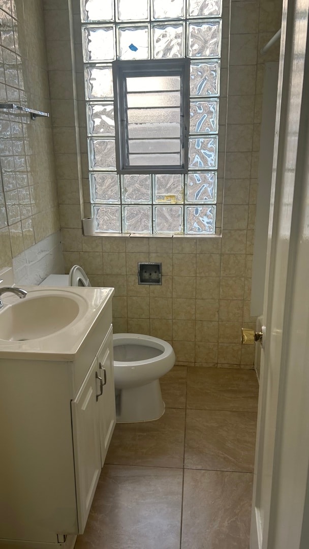 bathroom with tile walls, tile patterned floors, vanity, and toilet