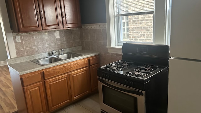 kitchen with range with gas cooktop, white refrigerator, a wealth of natural light, and sink