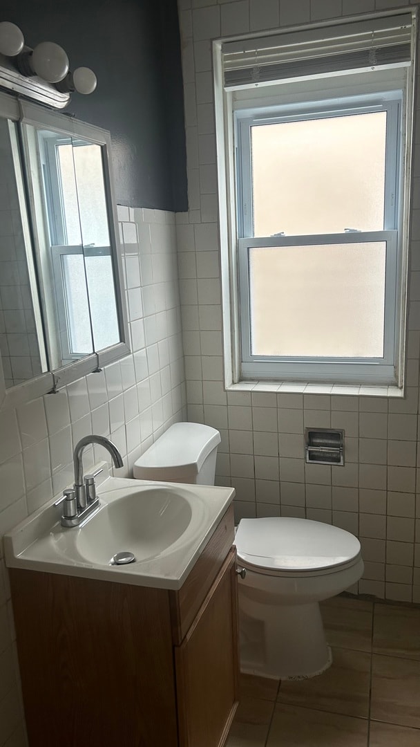 bathroom featuring vanity, tile patterned flooring, toilet, and a wealth of natural light