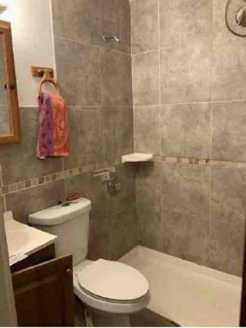 bathroom with tiled shower, vanity, toilet, and tile walls