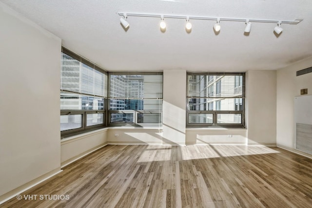 unfurnished room featuring a textured ceiling and light wood-type flooring