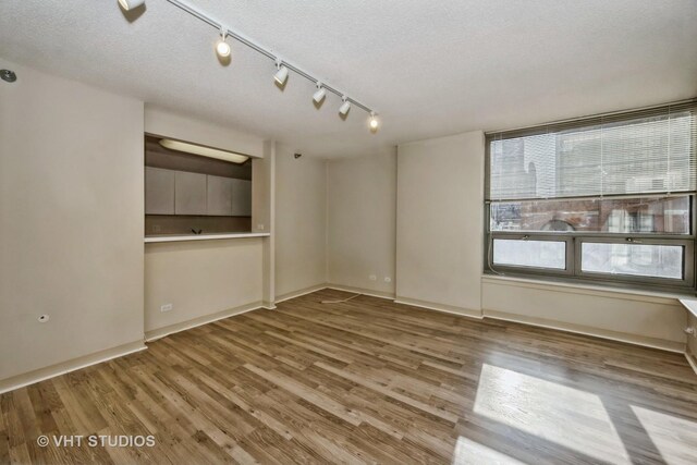 spare room with light hardwood / wood-style floors, rail lighting, and a textured ceiling