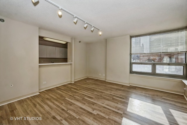 unfurnished room with wood-type flooring and a textured ceiling