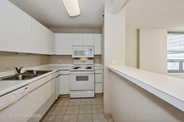 kitchen featuring sink, white cabinets, white appliances, light tile patterned floors, and a textured ceiling