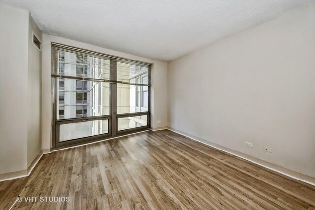 spare room featuring a textured ceiling and hardwood / wood-style floors