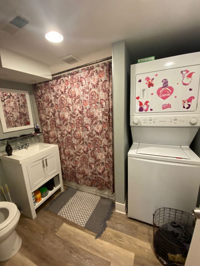 clothes washing area with stacked washer / dryer, sink, and hardwood / wood-style floors