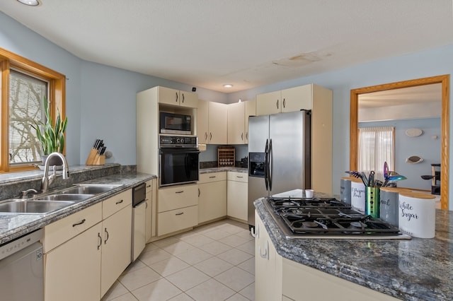 kitchen with appliances with stainless steel finishes, sink, light tile patterned floors, cream cabinets, and a textured ceiling