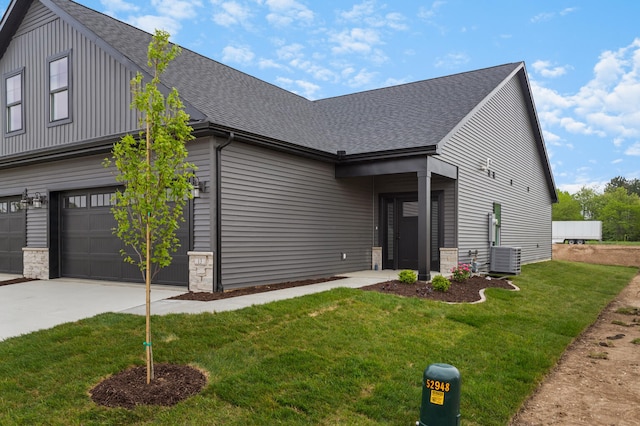 view of front of property featuring a garage, a front lawn, and central air condition unit