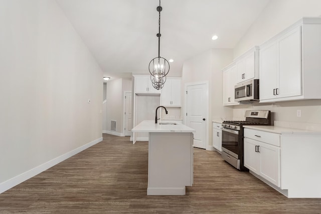 kitchen with pendant lighting, dark wood-type flooring, appliances with stainless steel finishes, sink, and an island with sink