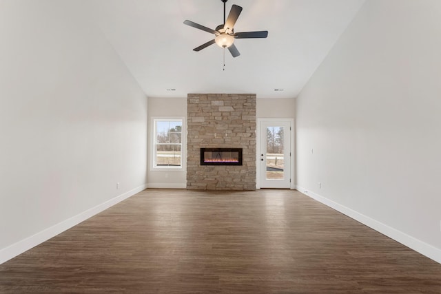 unfurnished living room featuring a stone fireplace, ceiling fan, and dark hardwood / wood-style floors