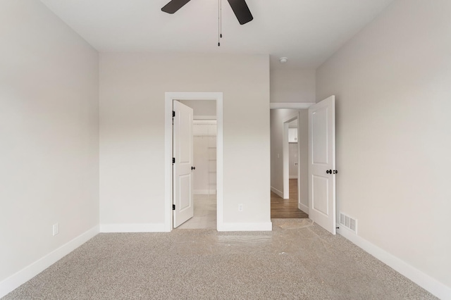 unfurnished bedroom featuring a closet, ceiling fan, a walk in closet, and light wood-type flooring