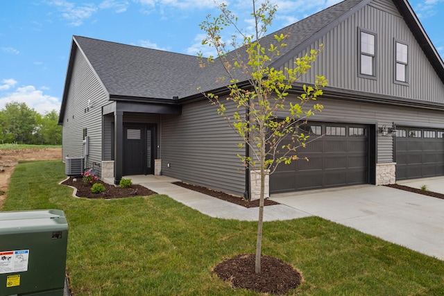 view of front facade featuring a garage, a front yard, and central AC unit