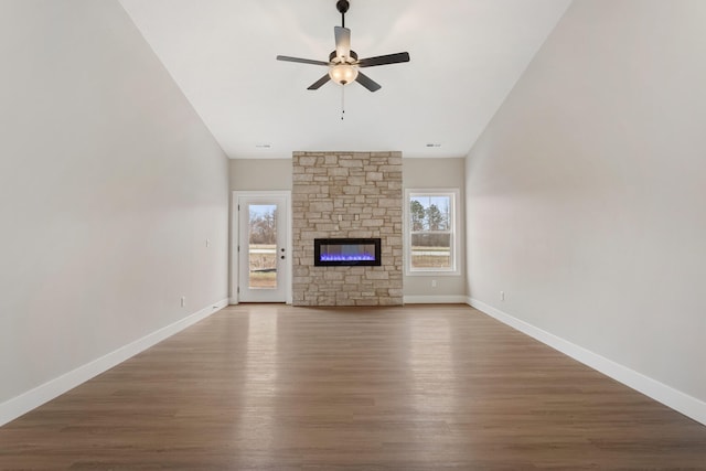 unfurnished living room featuring ceiling fan, a stone fireplace, and hardwood / wood-style flooring