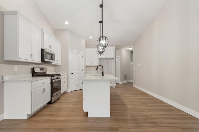 kitchen featuring light hardwood / wood-style flooring, appliances with stainless steel finishes, white cabinets, hanging light fixtures, and sink