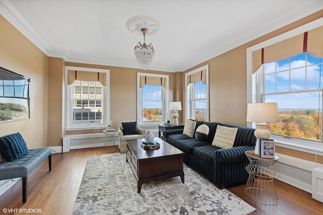 living room with an inviting chandelier, crown molding, and light wood-type flooring