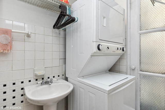 interior space featuring tile walls, stacked washer / dryer, and sink