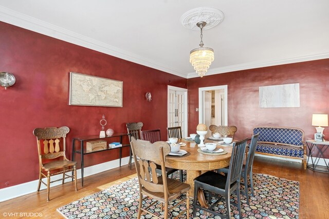 dining space with an inviting chandelier, ornamental molding, and hardwood / wood-style floors