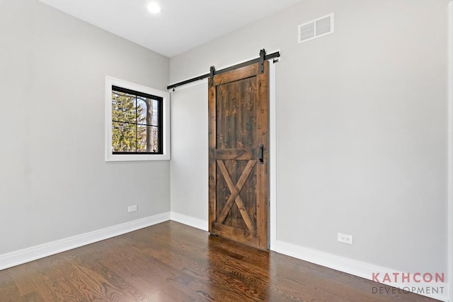 unfurnished room featuring a barn door and dark hardwood / wood-style floors