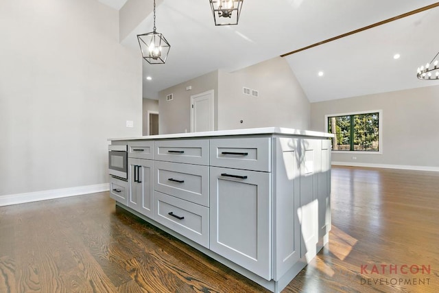 kitchen featuring a kitchen island, gray cabinets, dark hardwood / wood-style flooring, hanging light fixtures, and a chandelier