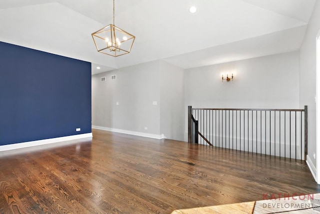 unfurnished room with lofted ceiling, dark hardwood / wood-style floors, and an inviting chandelier