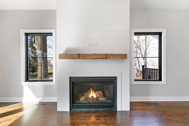 interior details with dark hardwood / wood-style flooring and a large fireplace