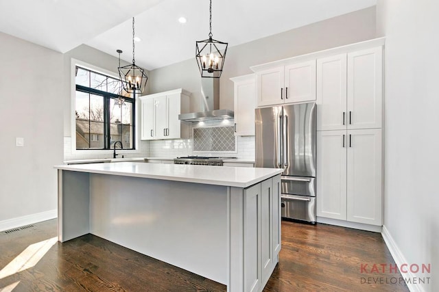 kitchen featuring dark hardwood / wood-style floors, a center island, wall chimney exhaust hood, and high end refrigerator