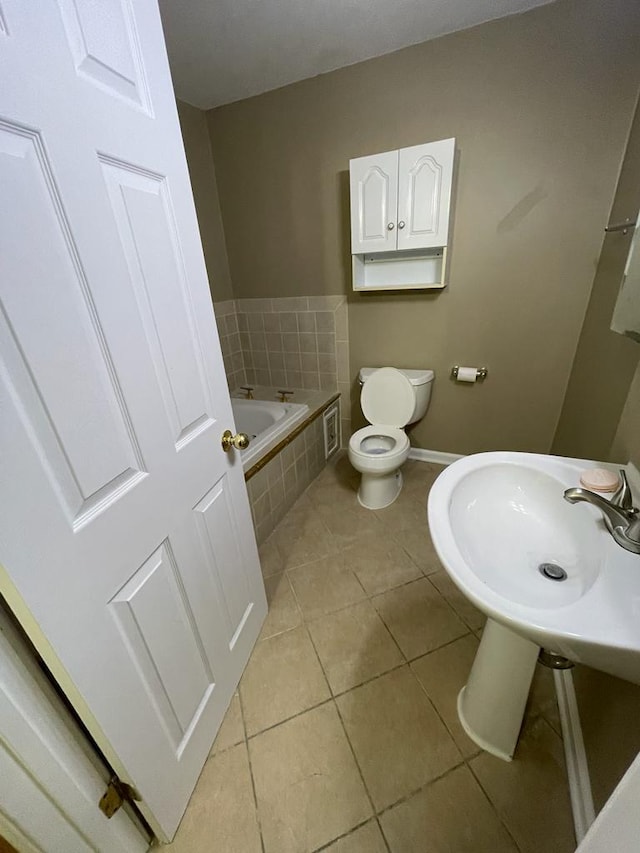 bathroom with toilet, tile patterned flooring, and tiled tub