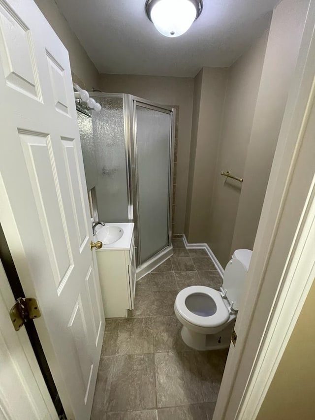 bathroom featuring vanity, toilet, and a shower with door