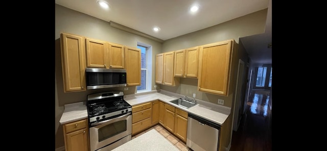 kitchen featuring stainless steel appliances, light tile patterned flooring, sink, and light brown cabinetry