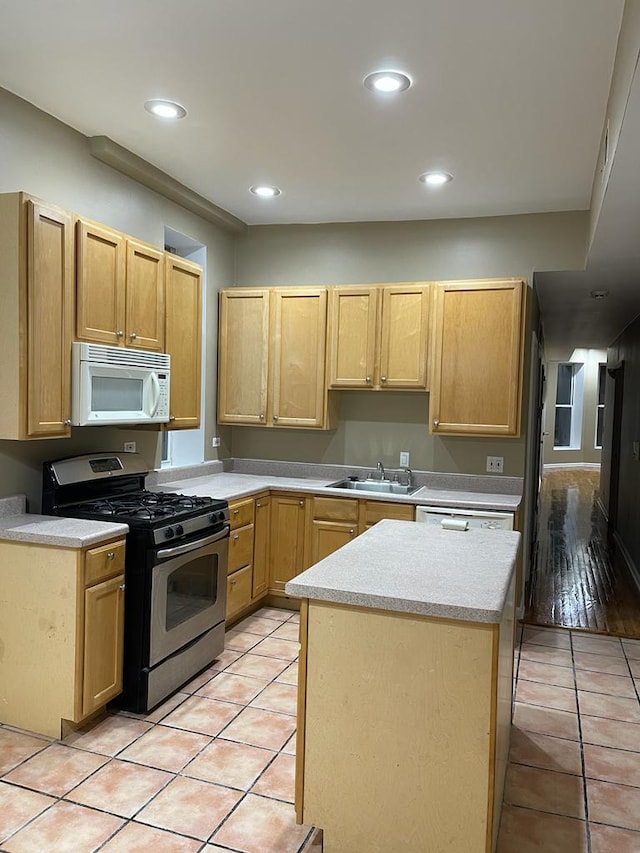 kitchen with light brown cabinetry, light tile patterned floors, white appliances, and sink