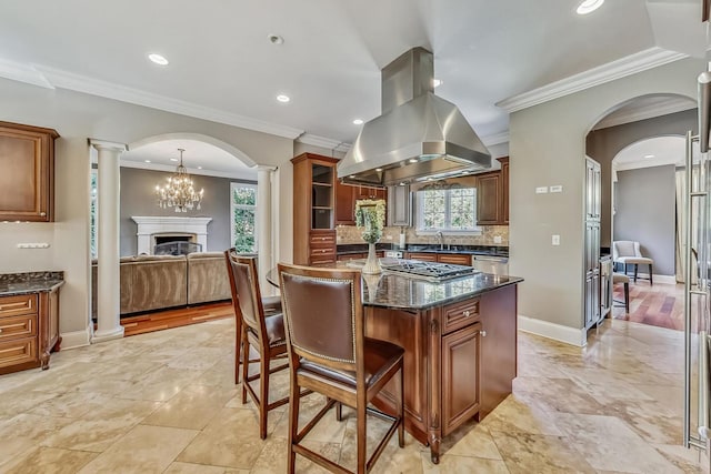 kitchen featuring backsplash, island range hood, dark stone counters, and crown molding