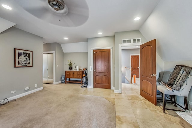 foyer with ceiling fan, light colored carpet, and lofted ceiling