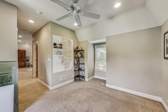 empty room with ceiling fan, vaulted ceiling, and light carpet